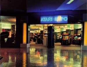 Neon-lighted entrance of Atari Expo arcade with customers playing games in Eastridge Mall - San Jose, CA