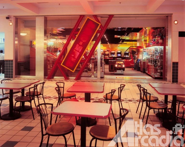 Tables and chairs sit outside the Time-Out arcade entrance with red, tilted sign and games visible inside the arcade