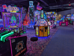 Neon-lit Round1 arcade floor with Wonka Claw, Tower Tickets, and Jackpot Racer machines