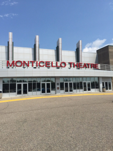 Exterior of Monticello Theatre with a red "MONTICELLO THEATRE" sign above glass entrance doors