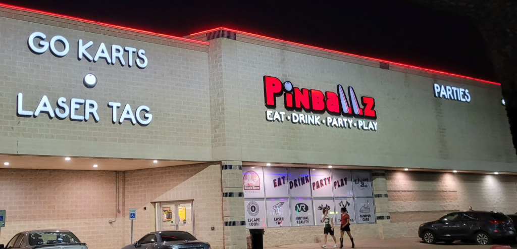 Pinballz entertainment center at night, with signs for Go Karts, Laser Tag, Parties, and Eat Drink Party Play