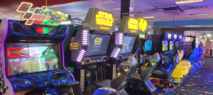 Row of arcade cabinets in a game arcade, including MotoGP motorcycle racing and Star Wars Battle Pod