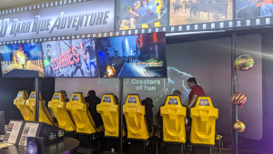 Rows of yellow 4D theater seats facing screens showing zombie scenes from the XD Dark Ride Adventure